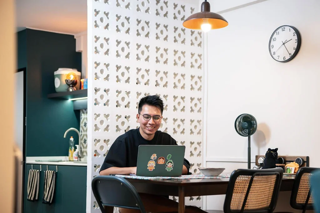 Home owner sitting at his dining table and looking at his laptop