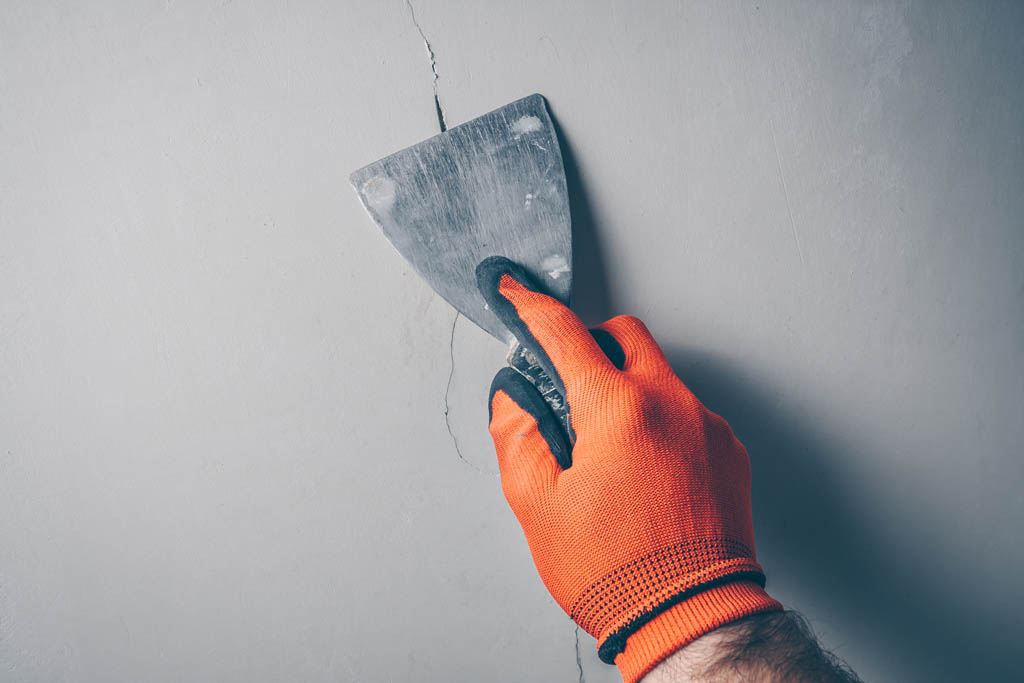 Worker repairs a crack in the wall 